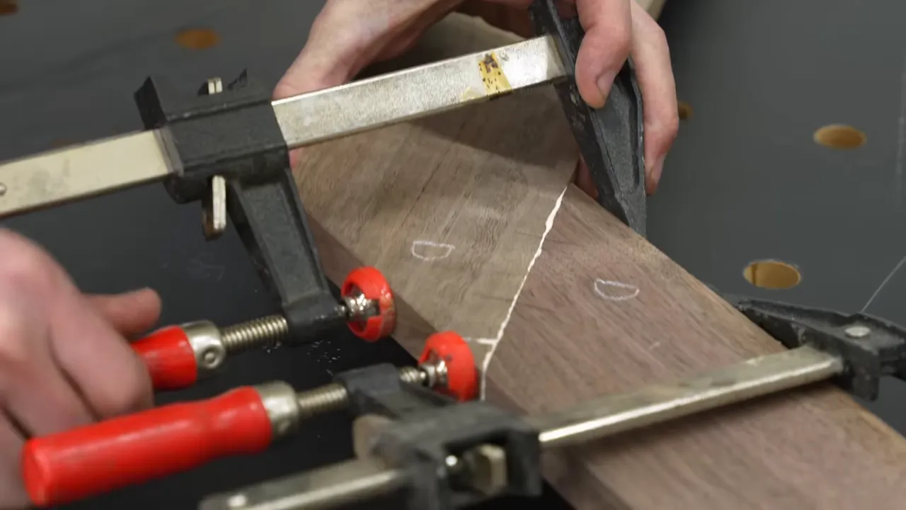 Clamps pressing an angled walnut frame joint against a temporary wooden block