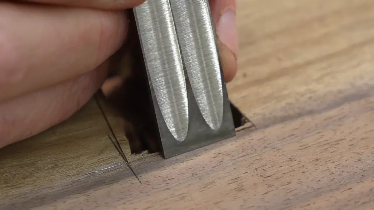 A chisel trimming the edge of a bow tie pocket beside the tabletop gap