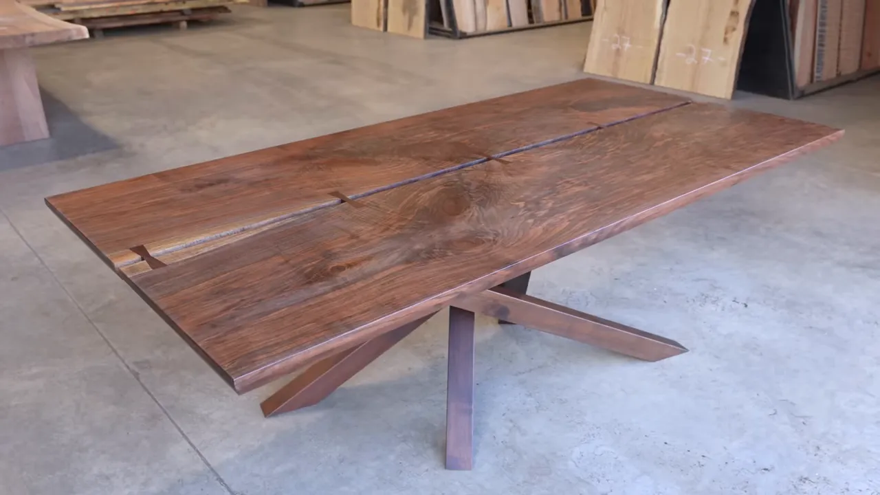 Finished walnut dining table with an open center seam and angular wooden spider base