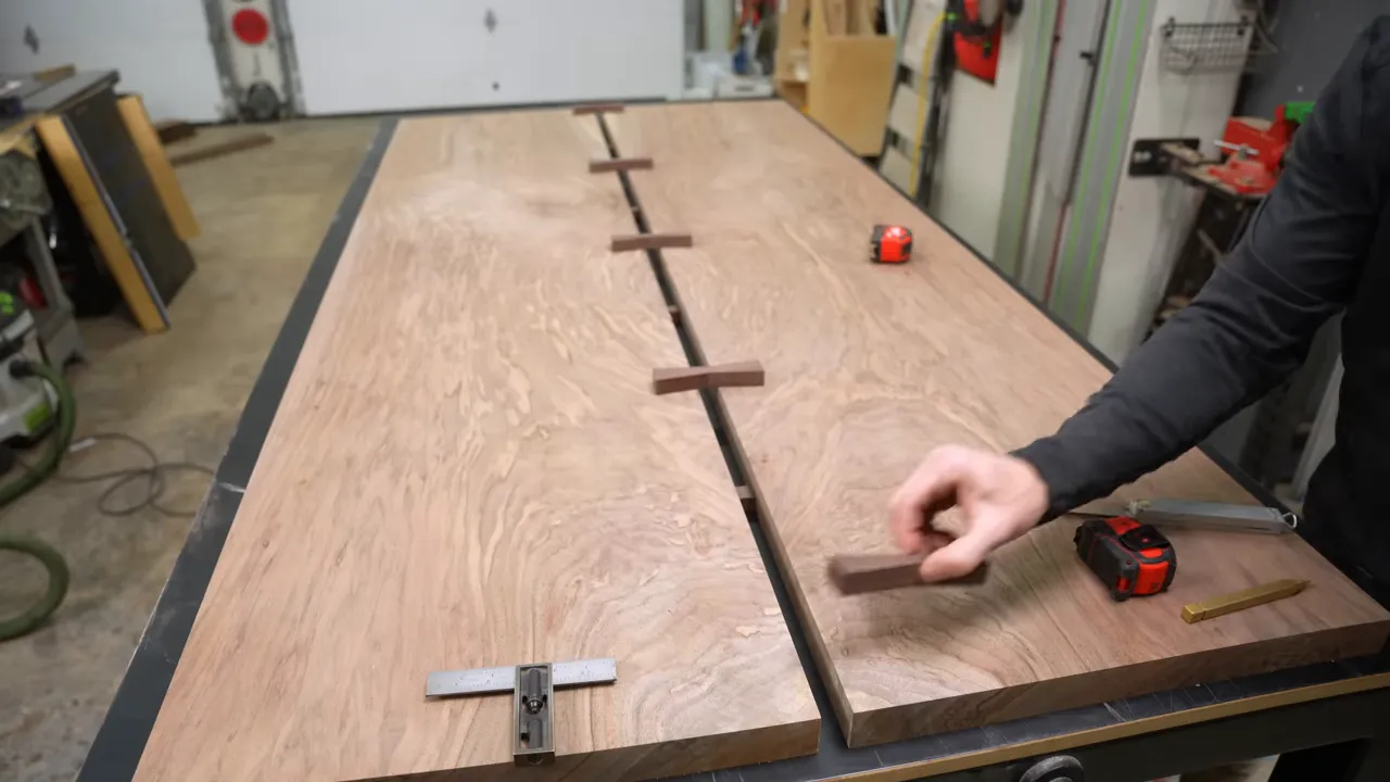 Five dark bow tie blanks arranged across the central gap in a walnut tabletop