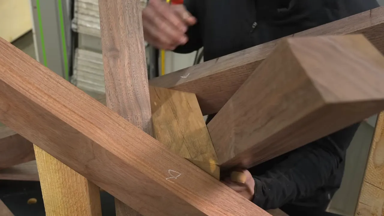 An angled walnut center block fitted between intersecting wooden legs