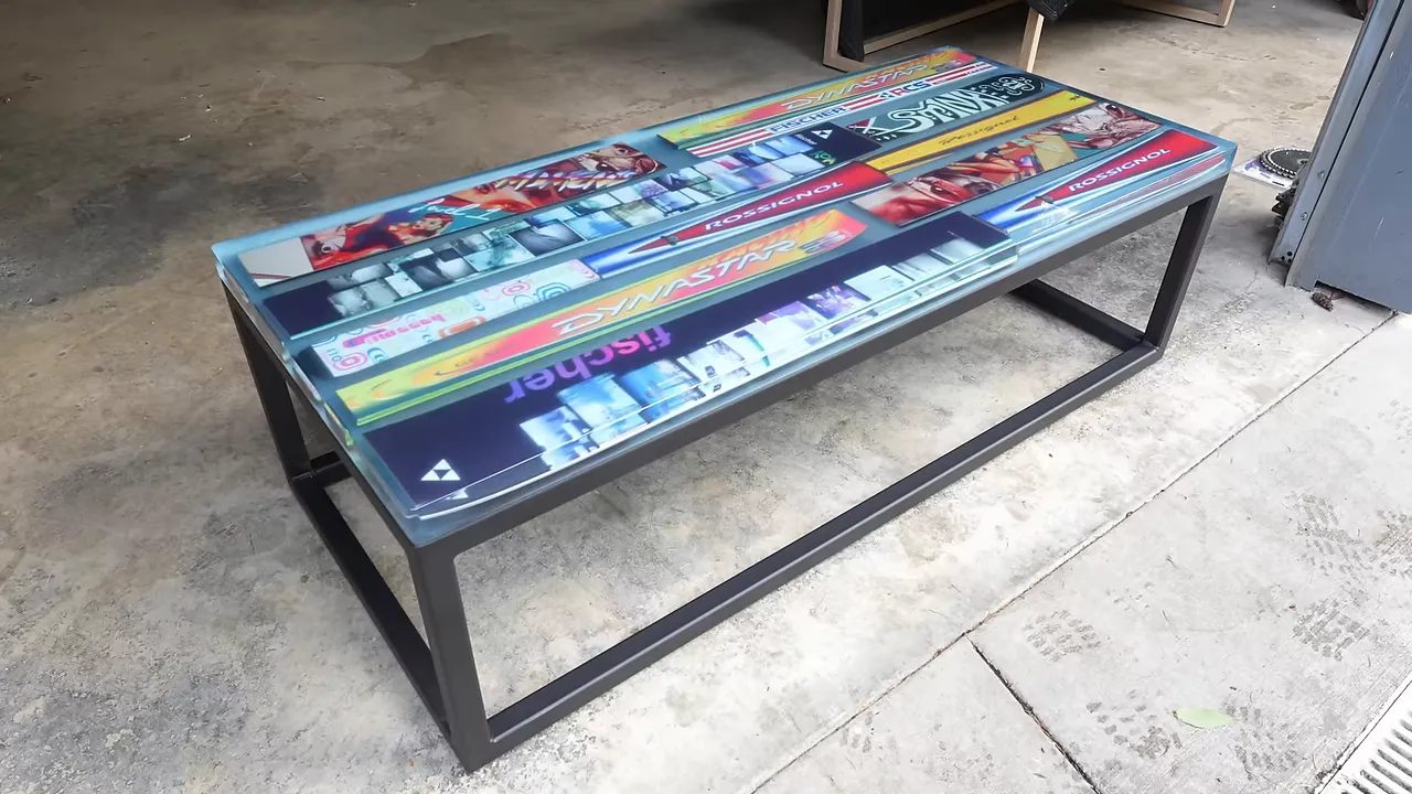 Finished ski coffee table with a glossy blue-tinted epoxy top and black rectangular steel base