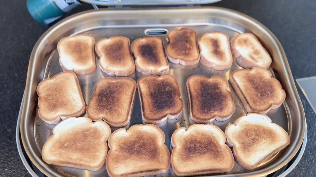 Bread slices covering the griddle with darker browning in the center and lighter browning near the edges