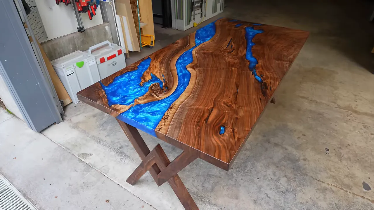Finished walnut dining table with metallic blue epoxy rivers and wooden crisscross legs