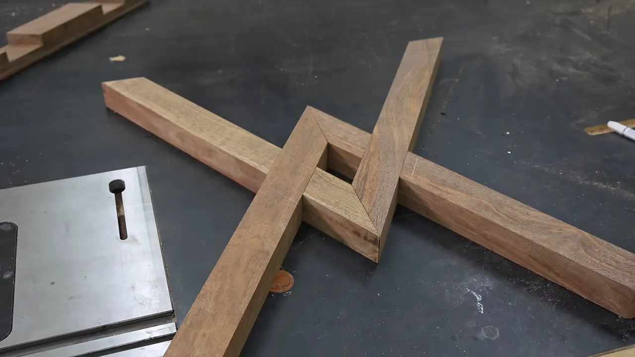 Interlocking walnut leg pieces laid flat in a crisscross pattern on a workbench
