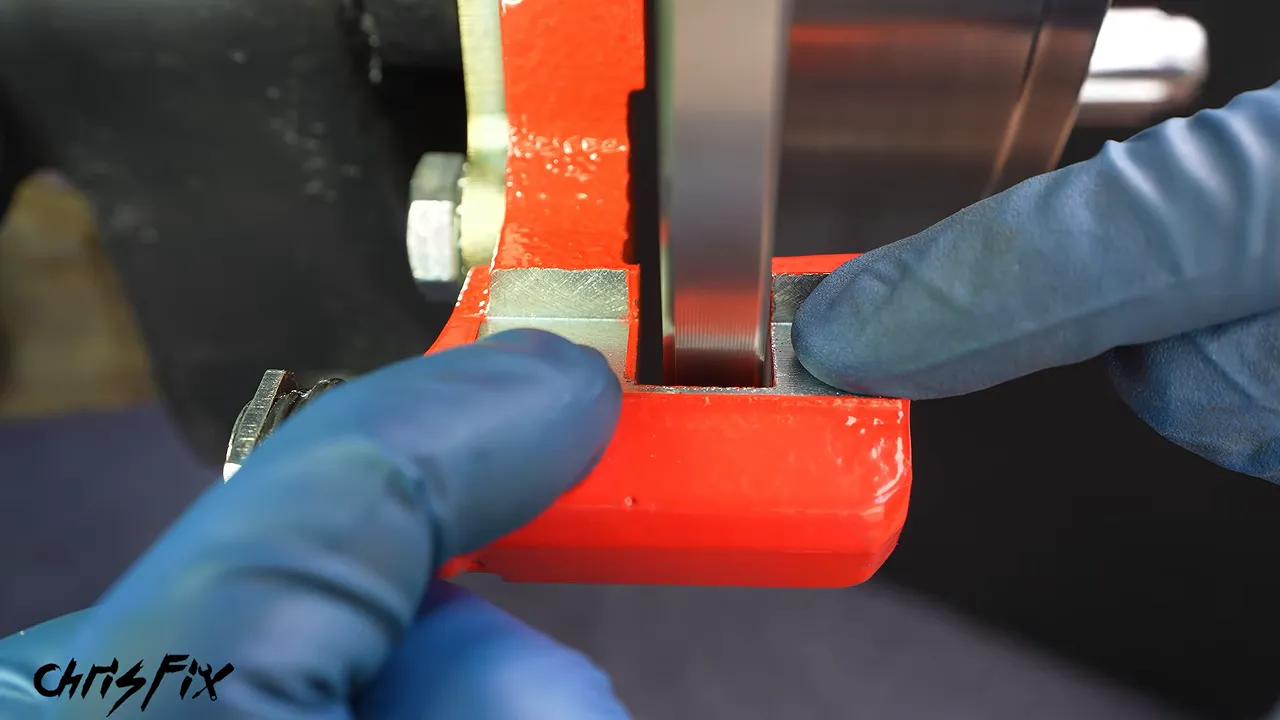 Close-up of the rotor inside the red caliper bracket with unequal side clearances