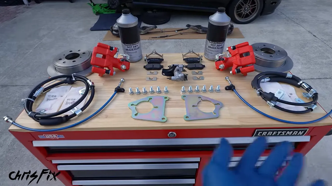 Rotors, red calipers, brake hoses, pads, and adapter plates arranged on a workbench