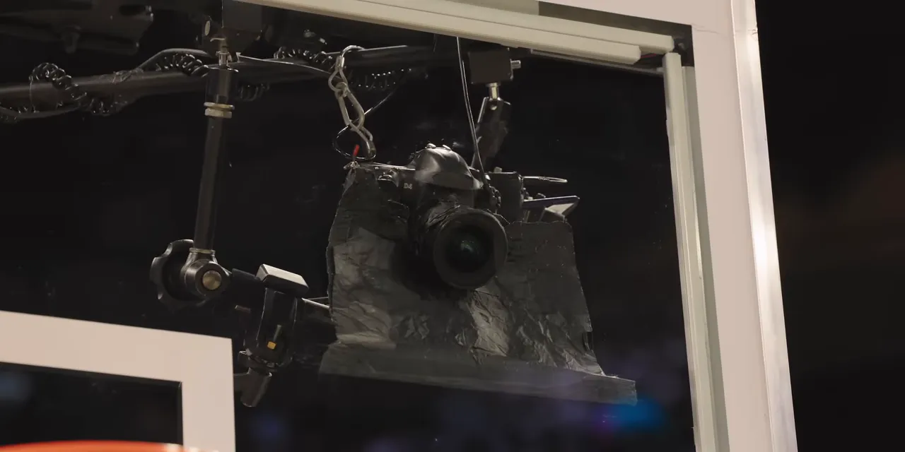 Still camera mounted behind the backboard with a black surround around its lens