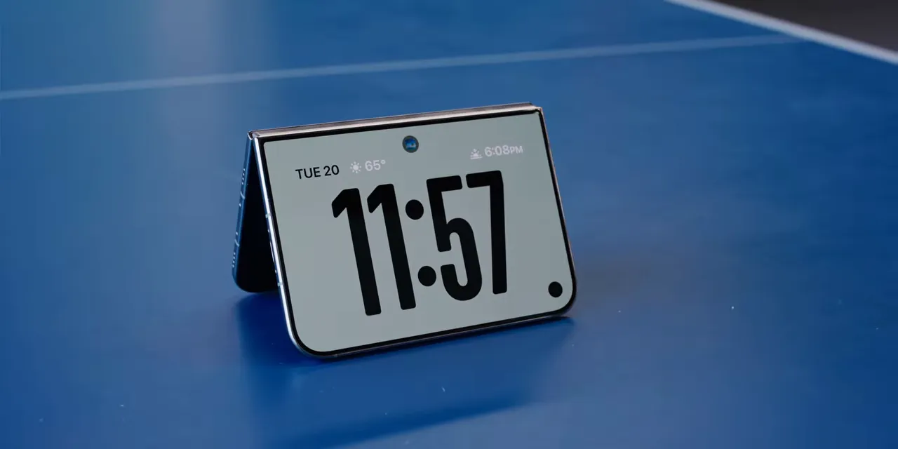 A partially folded phone standing on a blue table with a large clock display
