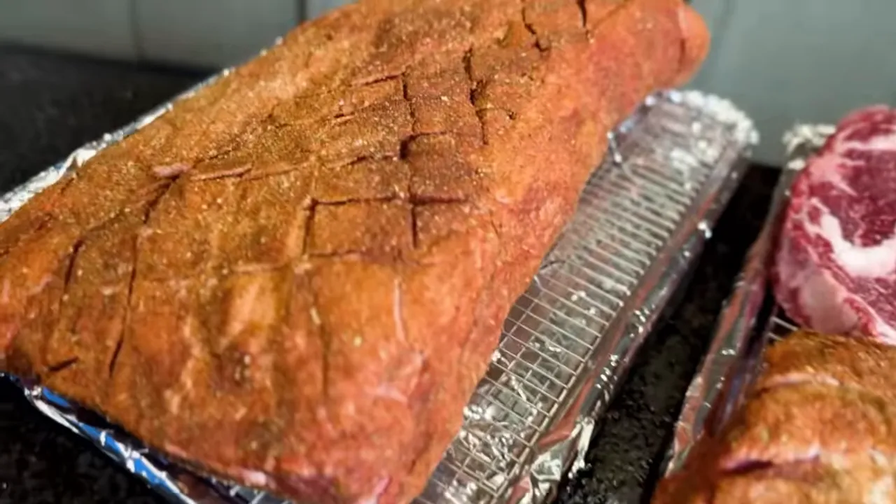 Seasoned beef roast with a crosshatched fat cap on a foil-lined tray