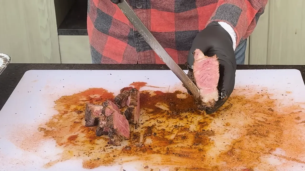 A cut steak held over a cutting board showing dark crust and a pink center