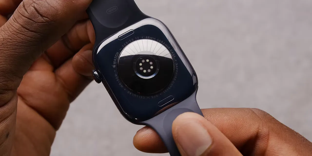 Hands holding an Apple Watch with its circular rear sensor array facing upward
