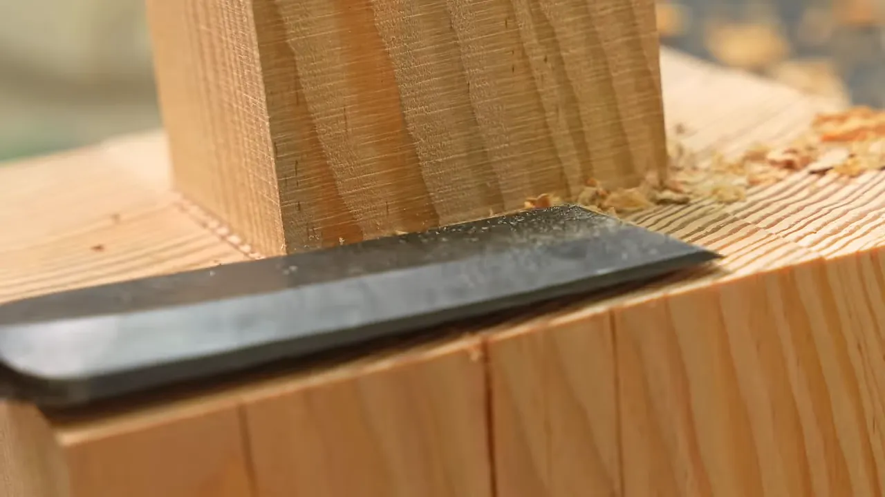 Wide timber slick paring the shoulder beside a square wooden tenon