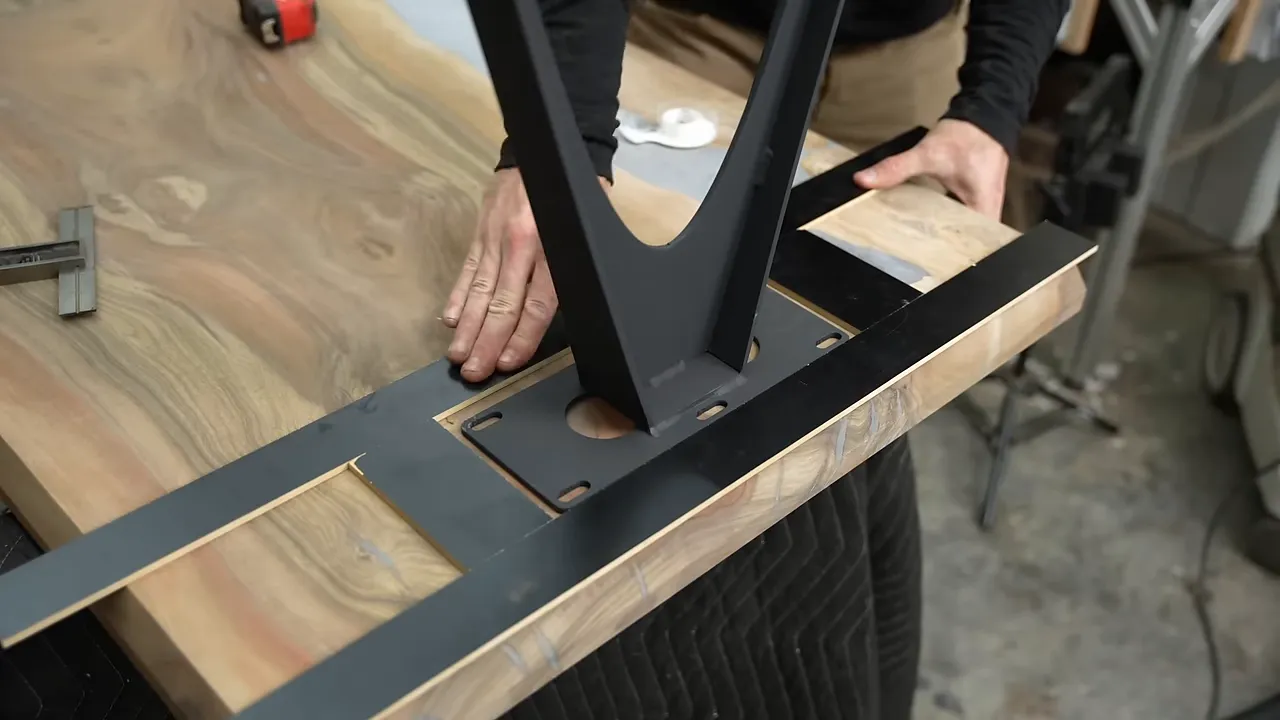 Thin black guide strips arranged around a metal table base on the underside of a tabletop