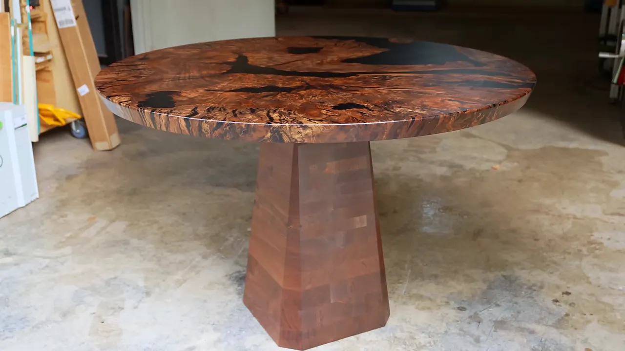 Finished round wood and black epoxy table on a tapered walnut pedestal in the workshop