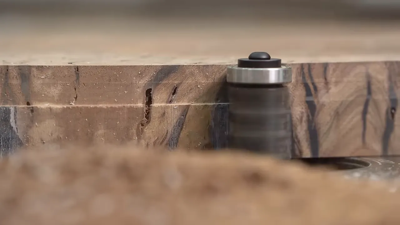 Flush-trim router bit beside the layered edge of a round wood tabletop