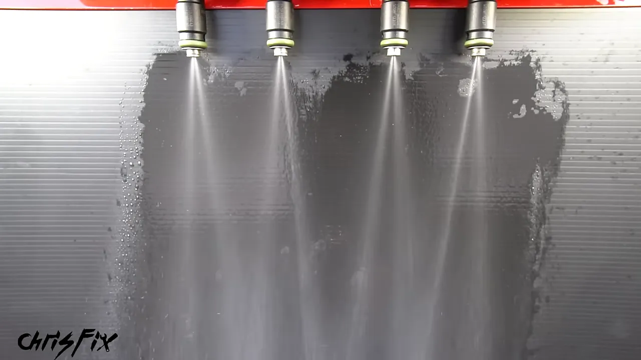 Four fuel injectors producing cone-shaped sprays on a test machine