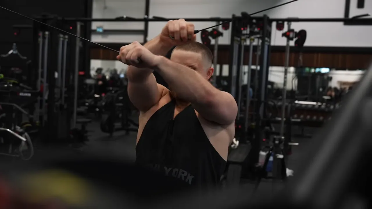 Reverse cable crossover with arms crossed in front of the upper body while holding the cable ends