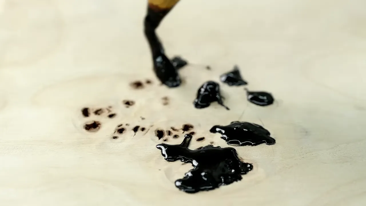 Hot-melt applicator placing black filler into a cluster of small holes in pale burl wood