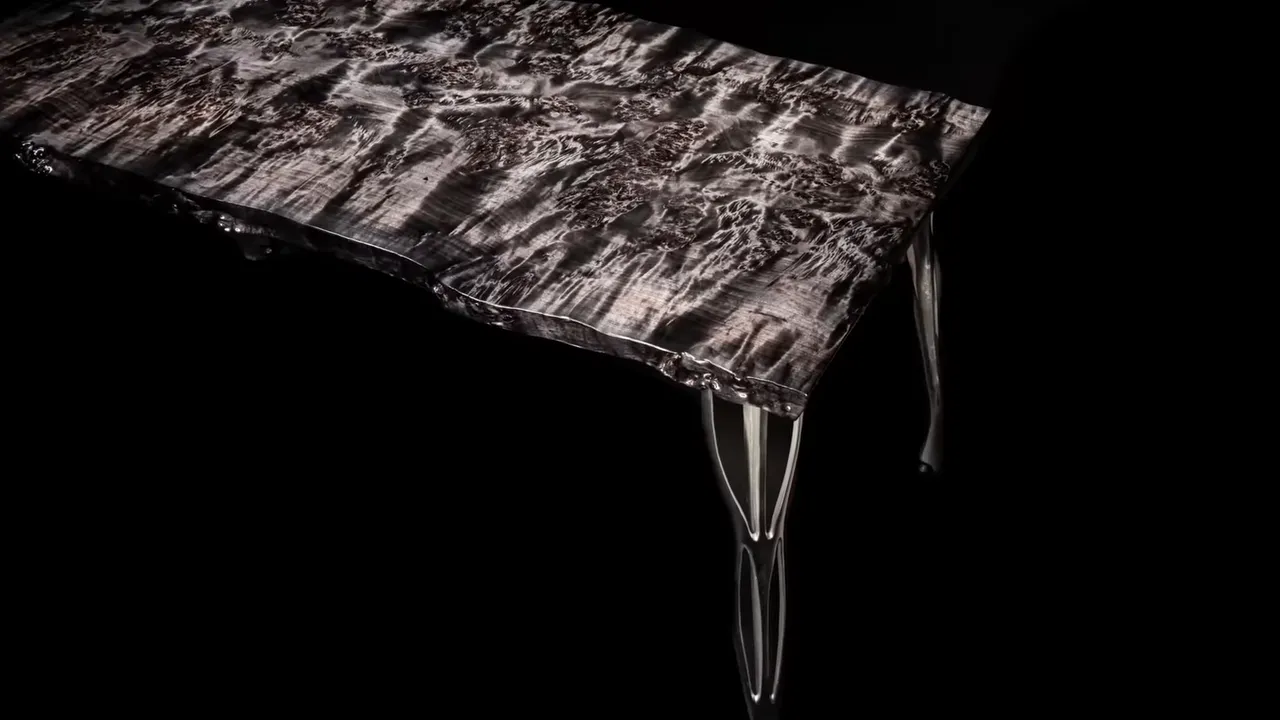 Finished black and gray figured live edge desk with polished metal legs against a black background