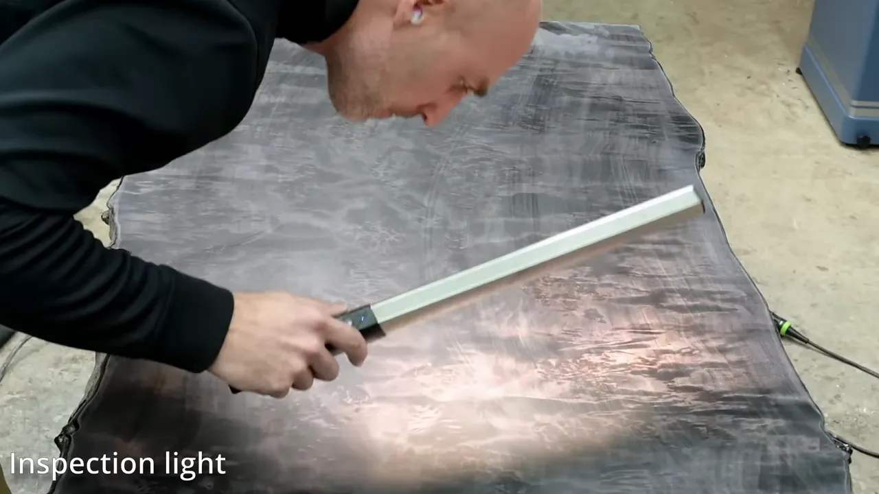 Handheld inspection light held close to the sanded black burl desktop