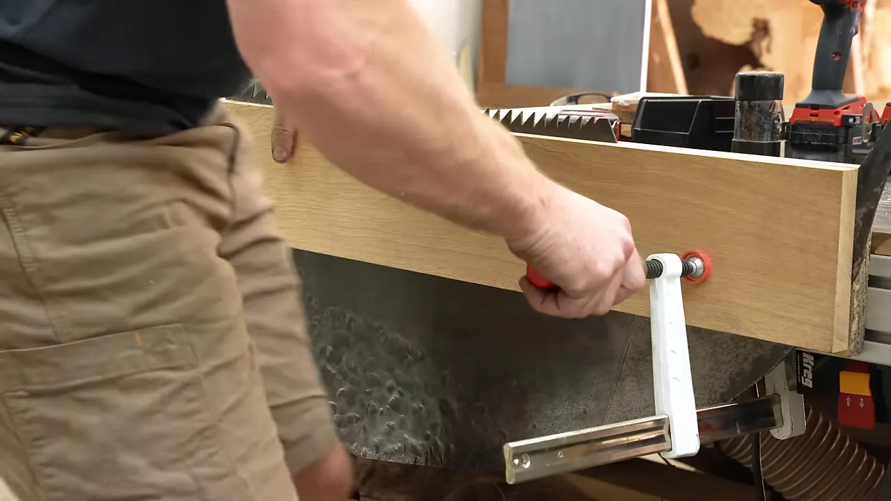 Large saw blade supported between two oak boards clamped to a workbench