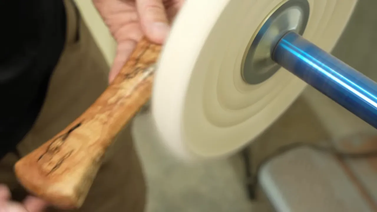 Polished spalted maple handle with black lines and a narrow curved grip