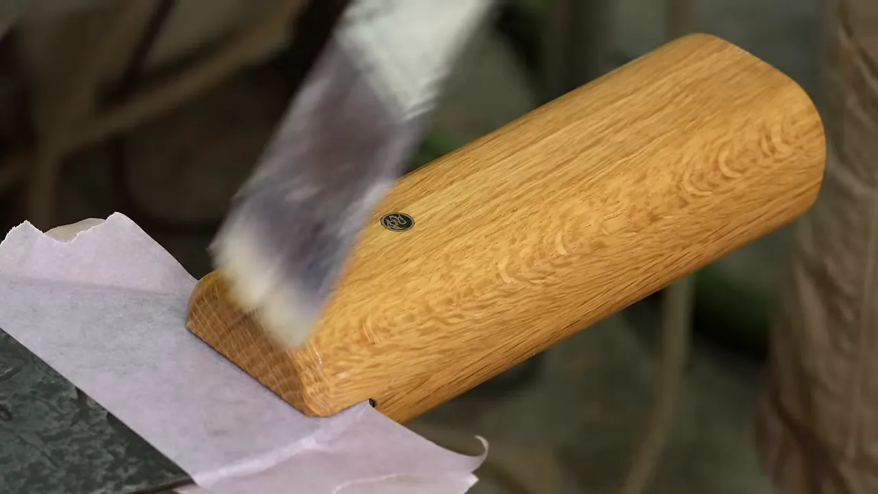Finished white oak saw handle beside the dark worn original wooden handle