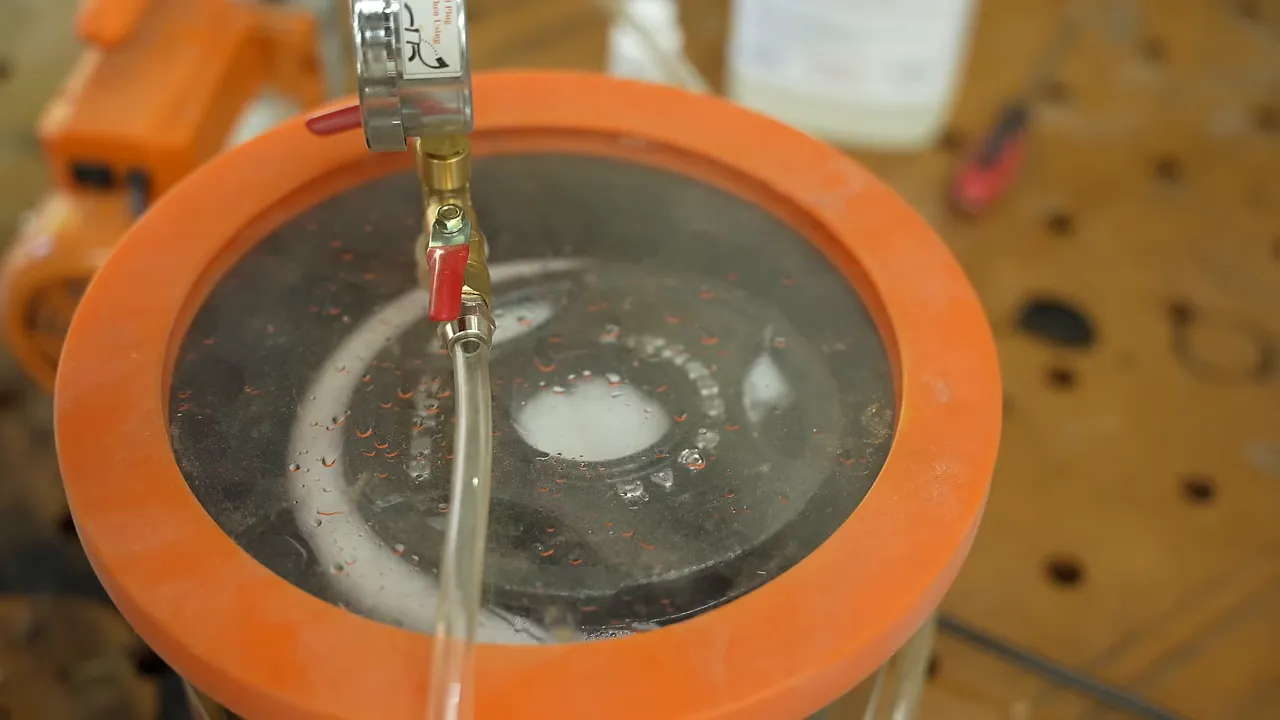 Bubbles and foam visible through the clear lid of a vacuum chamber