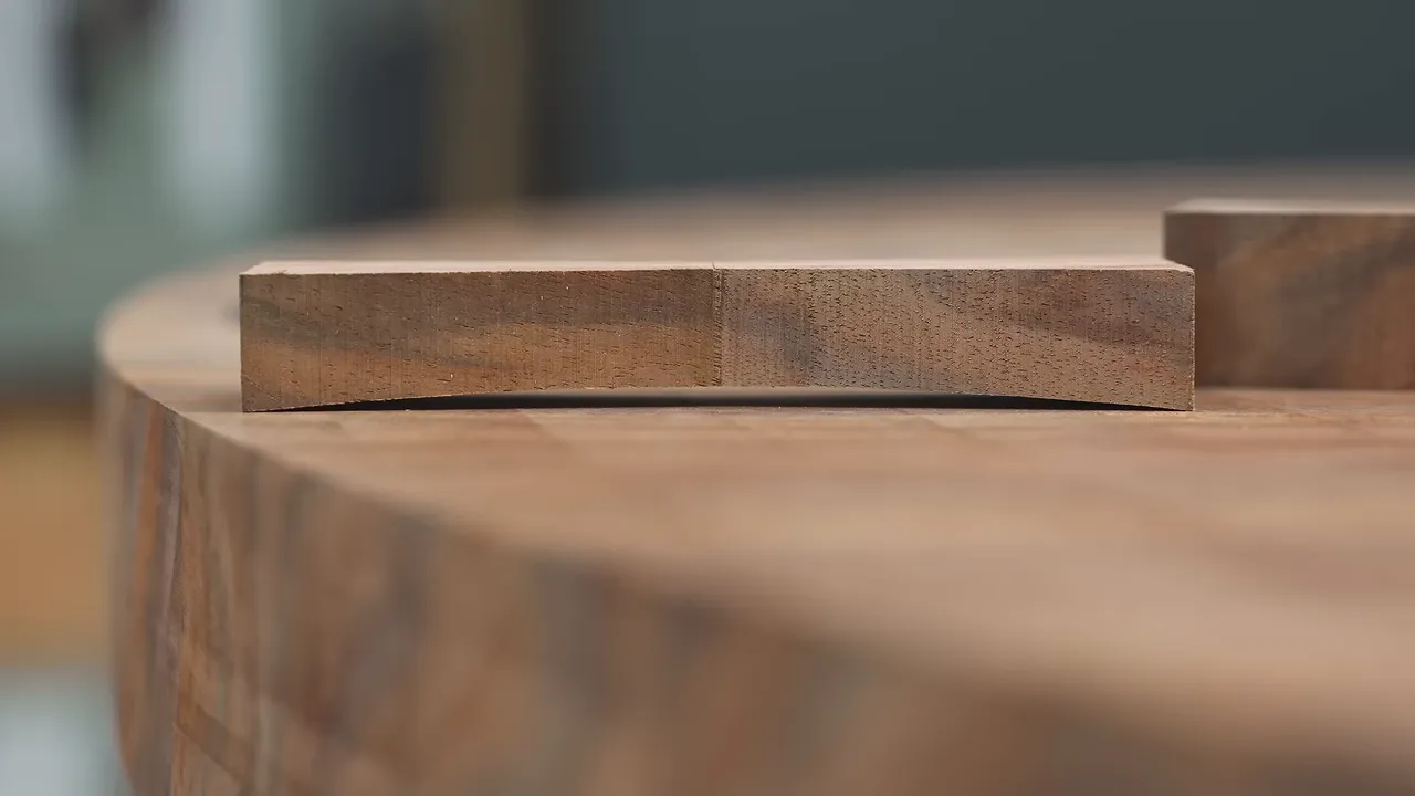 Thick bow tie blank resting against the curved perimeter of a walnut tabletop