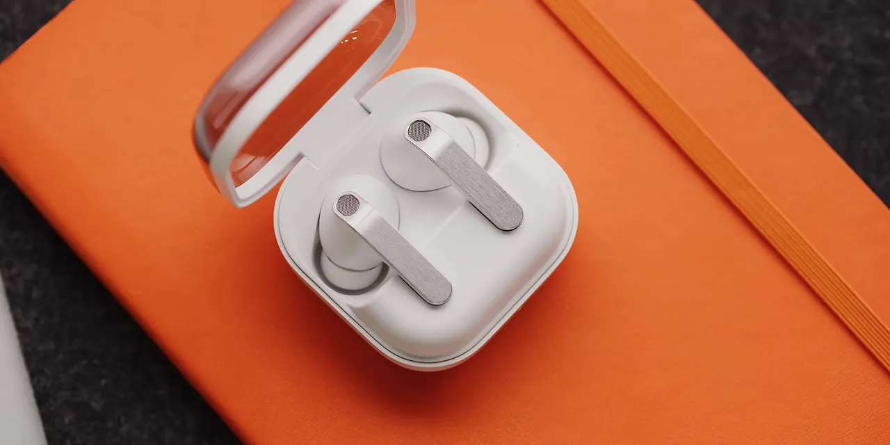 Open white Galaxy Buds case with a transparent lid and two earbuds inside on an orange notebook