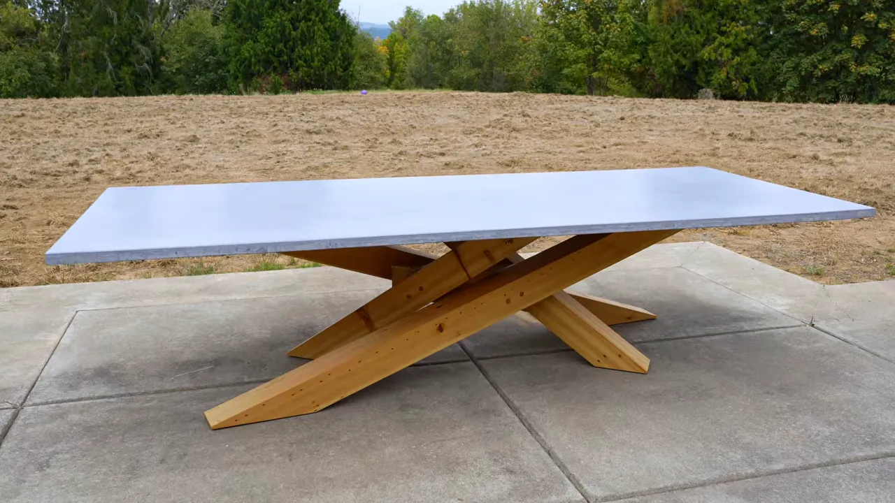 Large gray concrete outdoor dining table on an angular wooden base on a patio