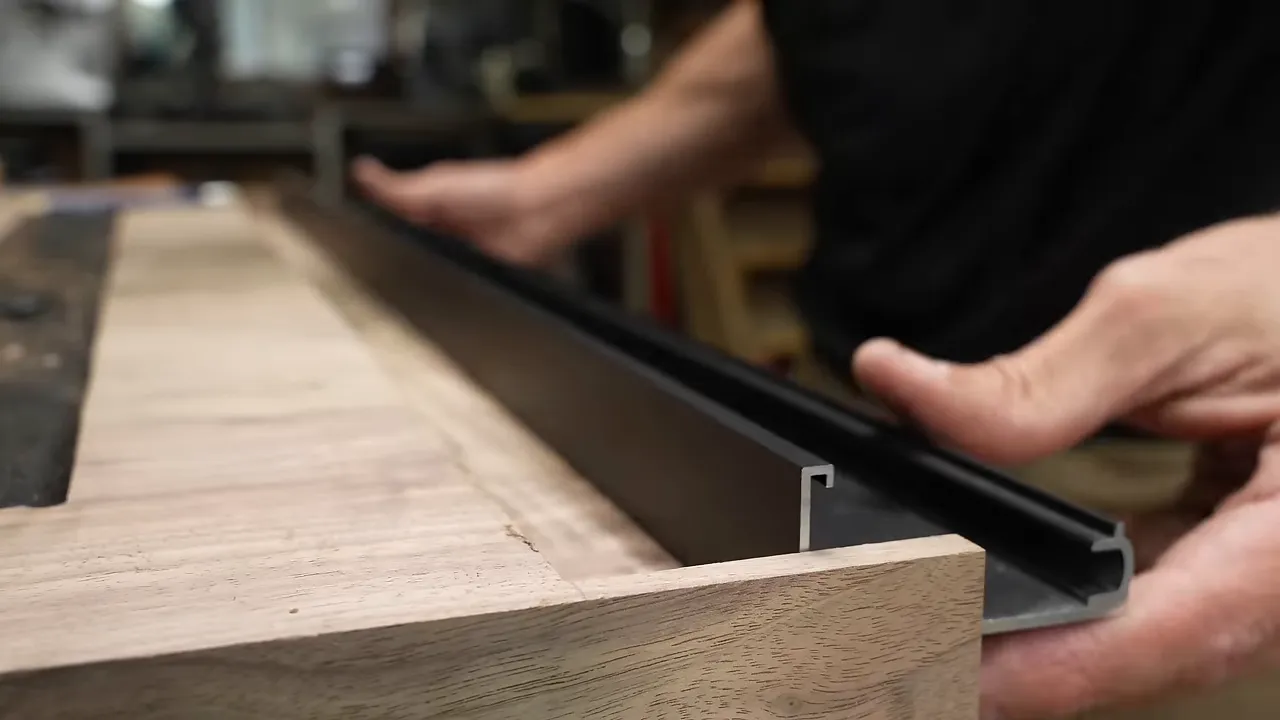 Black aluminum channel fitted into a routed recess with a wood end left intact