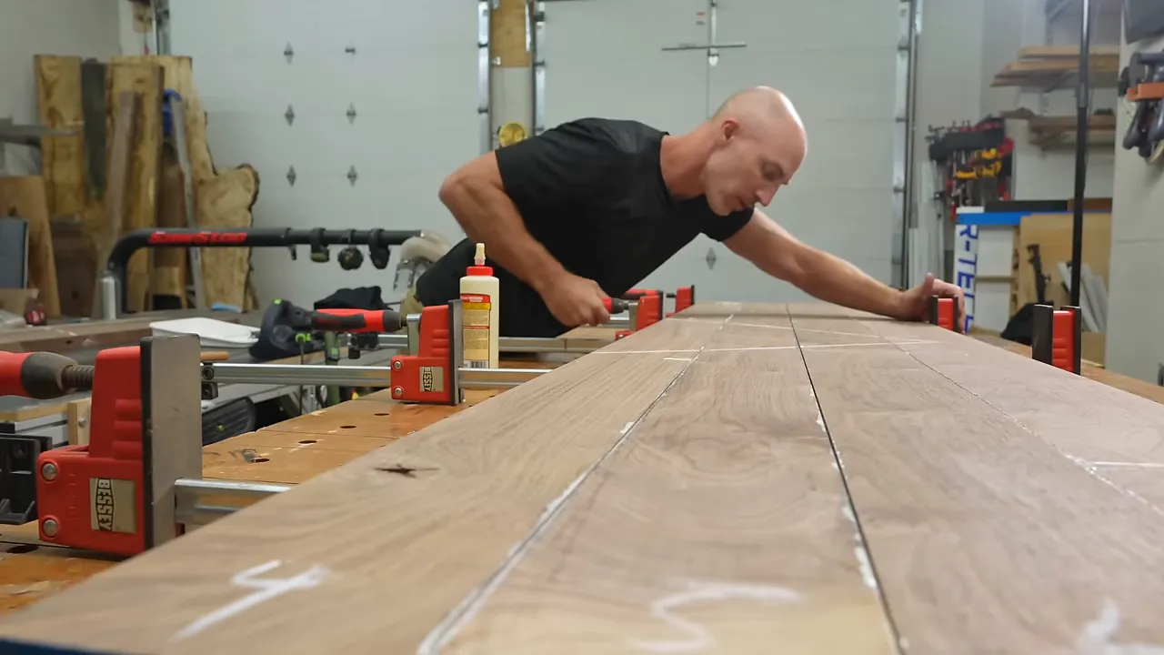 Walnut boards assembled into a panel with parallel clamps across the glue joints