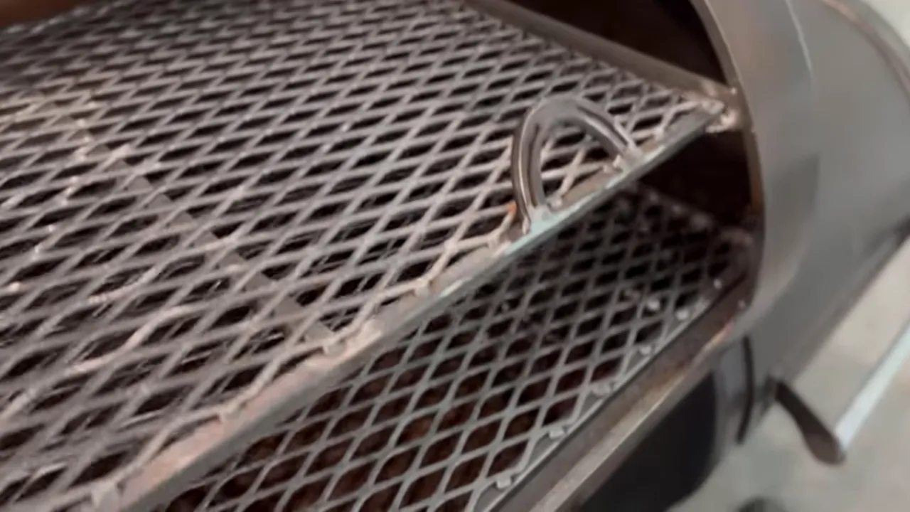 Upper and lower expanded-metal cooking racks inside an open cylindrical smoker