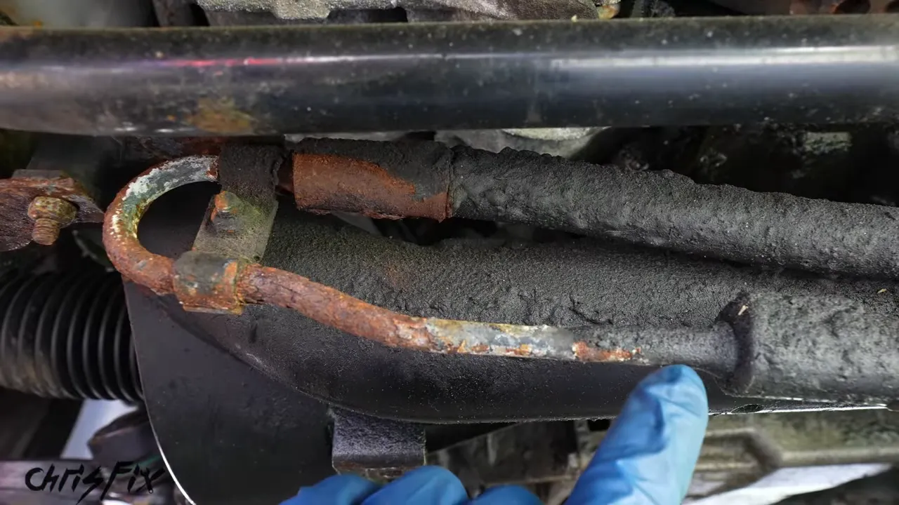 Rusted metal power steering line running beneath a black sway bar
