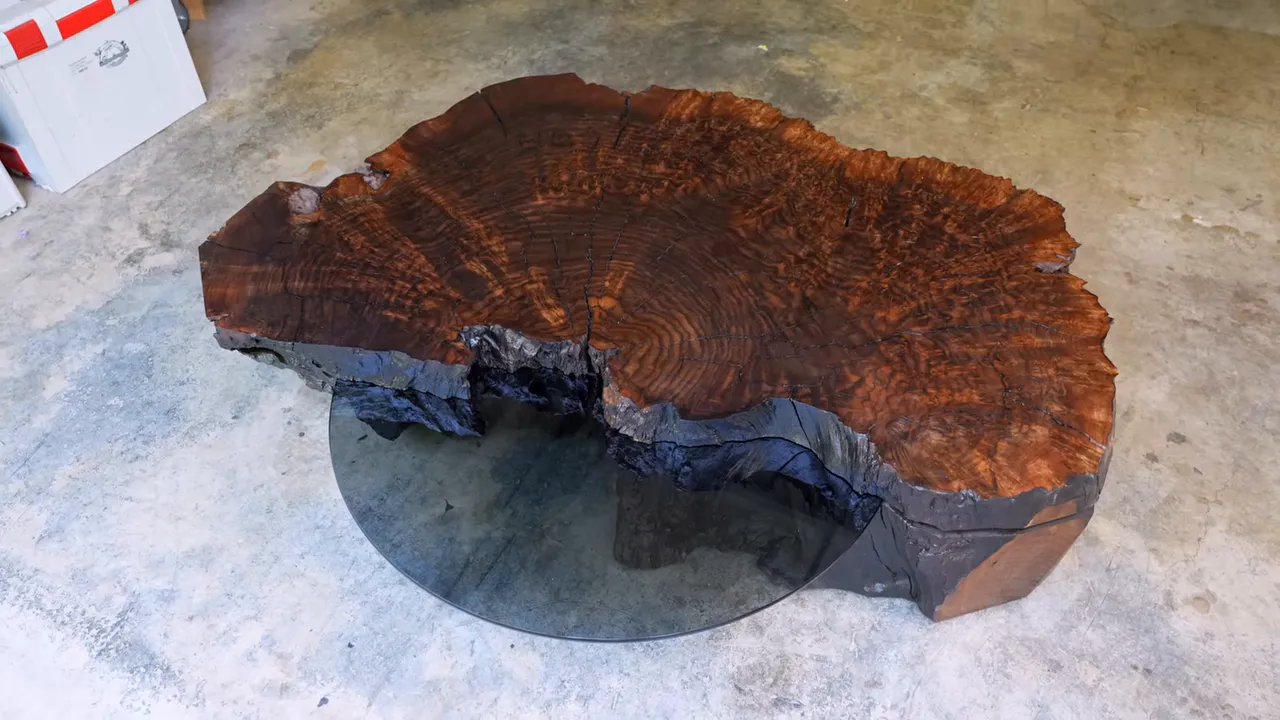 Finished walnut burl table with a black glass shelf projecting from the front