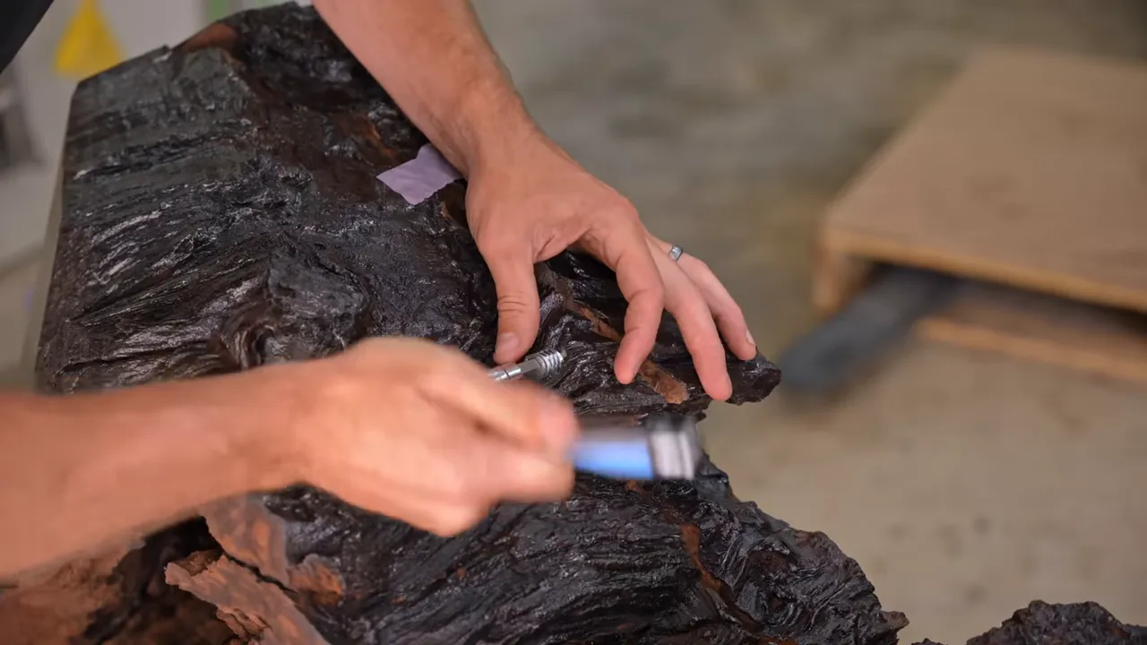 Hands adjusting hardware beside the narrow slot in the dark walnut edge