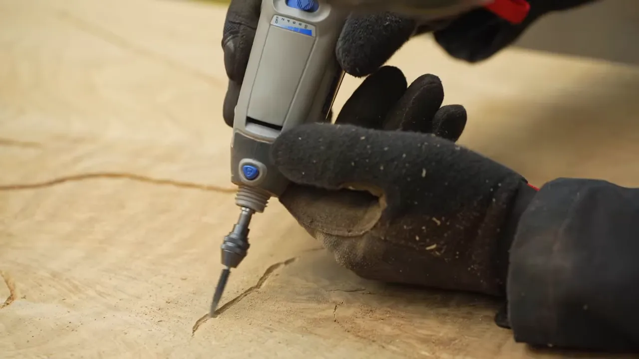 A small rotary tool widening a narrow crack in the oak surface