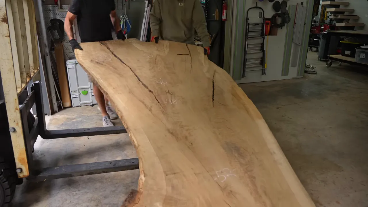 A large pale oak slab being lowered onto supports in the workshop