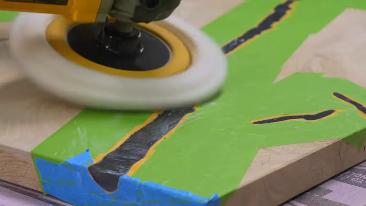 Green masking tape surrounding branching resin-filled cracks while a buffer polishes the exposed epoxy