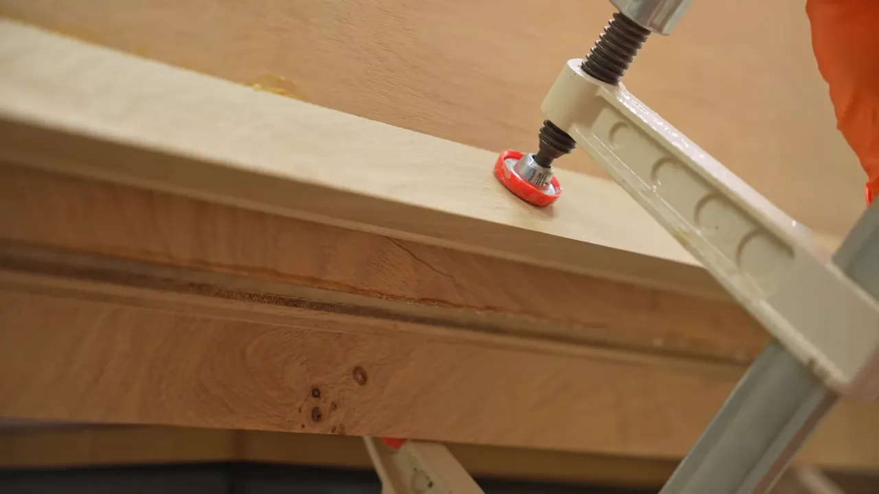 An angled clamping jig and clamp pressing the oak waterfall miter together