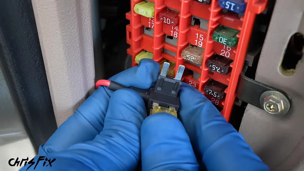 Close-up of a fuse tap beside the truck fuse box with a gloved finger indicating its fuse positions