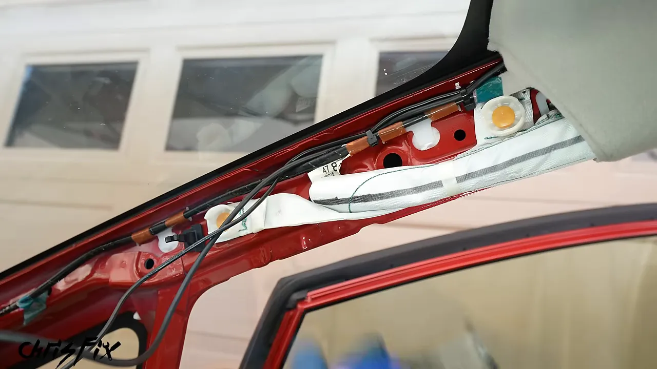Exposed A-pillar showing the curtain airbag and camera wires routed beside the factory harness