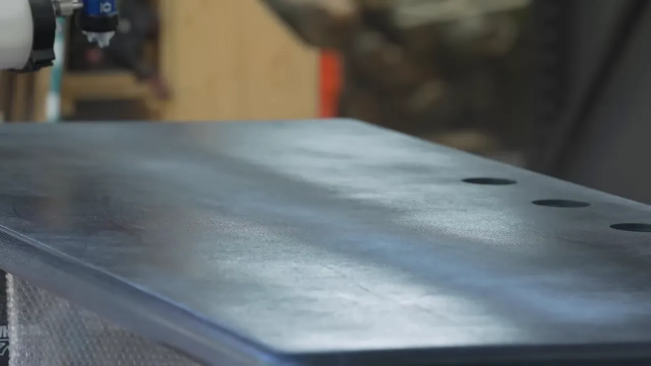 A spray gun applying clear finish to the blue denim tabletop
