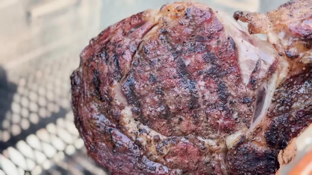 Close-up of a cooked tomahawk steak with a browned crust and dark grill marks