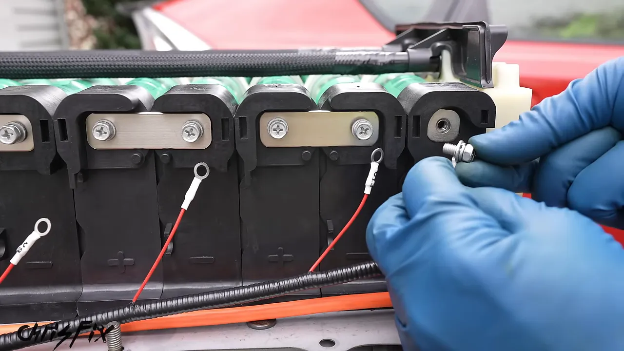 Close-up of a voltage-sensing ring terminal and orange cable attached beside the new battery busbars