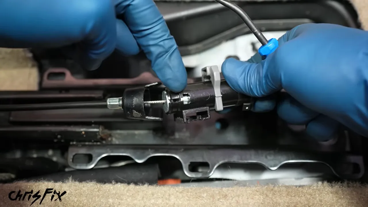 Gloved hands aligning the metal disc and cable opening beneath a seat rail