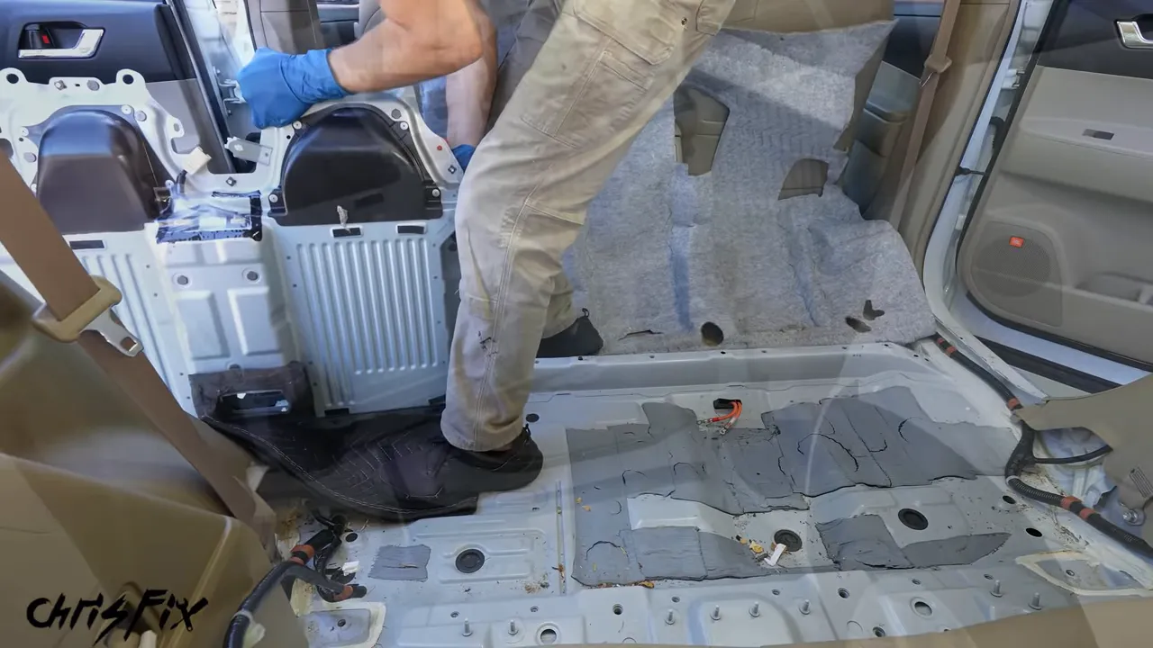 Two people lifting a hybrid battery assembly through the Highlander's rear doorway