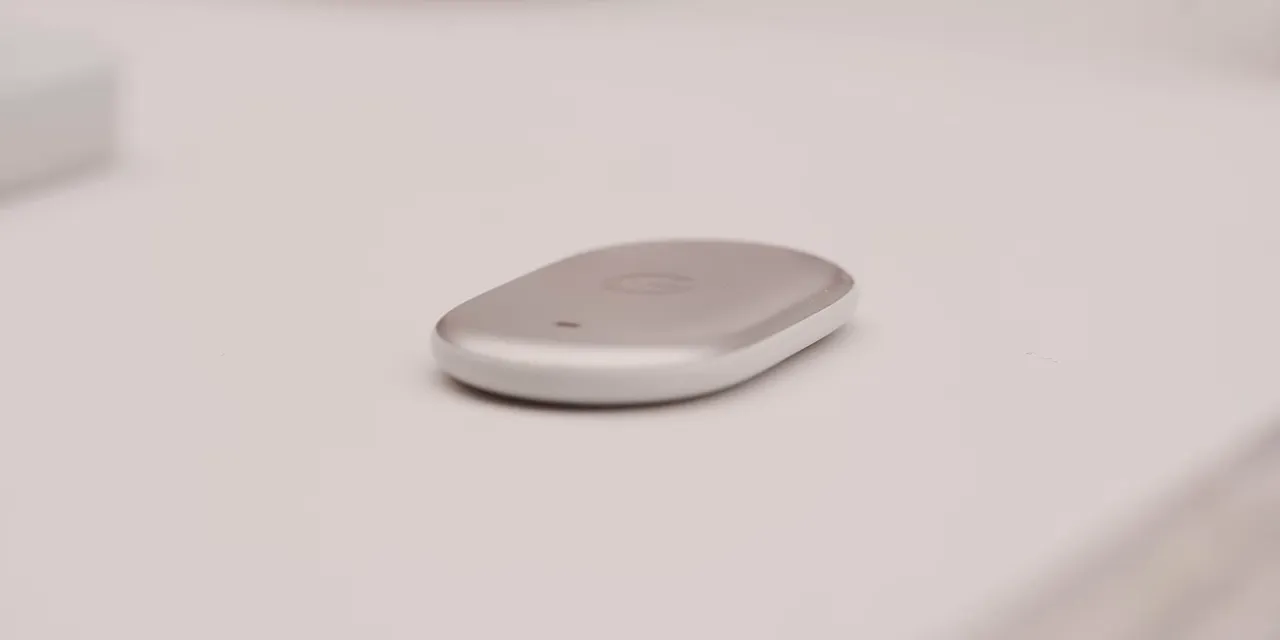 Small rounded white Google Tag held between fingers with a G logo visible